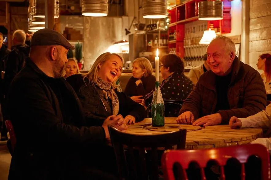 Vinir að hlæja við borð á hlýlega lýstum bar í Reykjavík